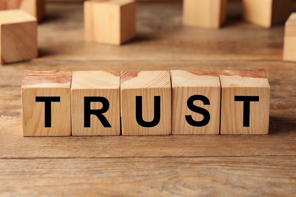 'Trust' spelled out in wooden blocks on a table.